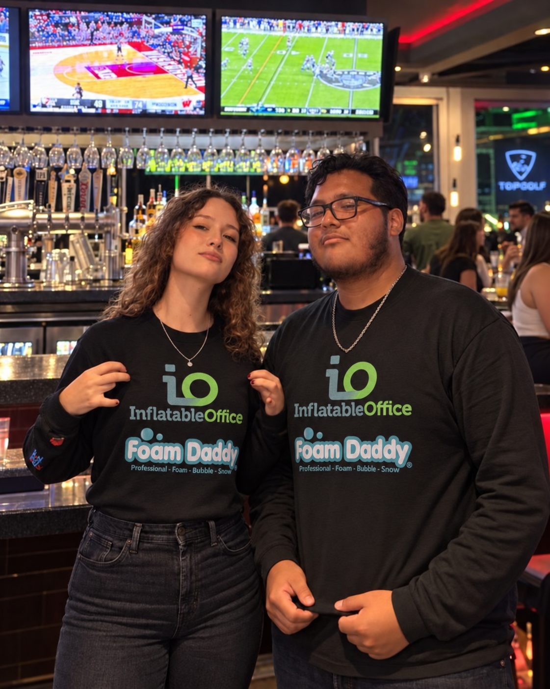 Two event staff at the Topgolf bar wearing black Inflatable Office and Foam Daddy sponsor shirts