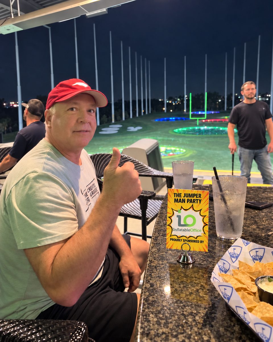 Tabletop sign at Topgolf reading The Jumper Man Party, proudly sponsored by Inflatable Office